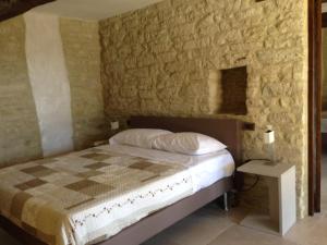 1 dormitorio con cama y pared de piedra en Villa Anna Heated Pool and two jacuzzi, en SantʼIppolito