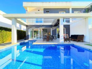 eine Villa mit einem Pool vor einem Haus in der Unterkunft Villa Bambu Gran Alacant by Villas&You in Gran Alacant