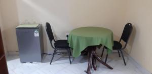 a green table with four chairs next to a refrigerator at Armaan Guest House in Diani Beach