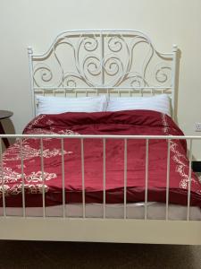 a bed with a metal frame and red sheets and pillows at Green Haven in Mbale
