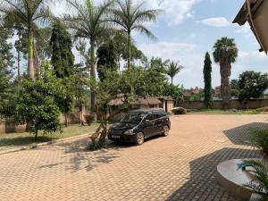 un coche aparcado en un aparcamiento con palmeras en Green Haven, en Mbale