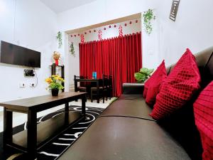 salon z kanapą z czerwonymi poduszkami i stołem w obiekcie Mesmerizing comfy condo with world class amenities w mieście Manipala