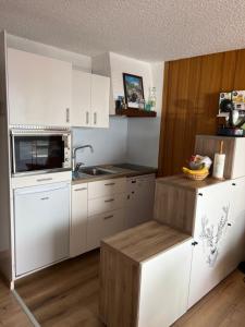 a small kitchen with white cabinets and a sink at Appartement station Orcieres merlette in Orcières