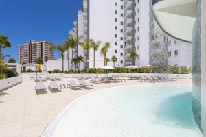 uma piscina com espreguiçadeiras e um edifício em Oceanfront Rental em Adeje