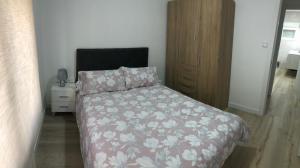 sypialnia z łóżkiem z kwiatową narzutą i szafką nocną w obiekcie PARQUE DE LA MARINA ESPAÑOLA w mieście Zamora
