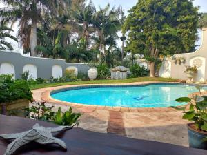 a swimming pool in a yard with palm trees at Baobab Suite - Villa Roc Guesthouse Salt Rock, Ballito, Solar Power in Salt Rock