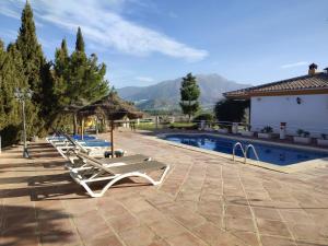 a row of lounge chairs next to a swimming pool at Casa Rocío&Paloma in Los Romanes