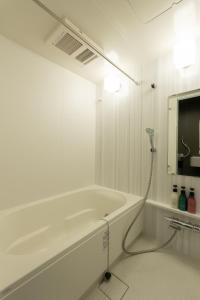 a white bathroom with a bath tub and a television at Japan Hinata Hotel 池下駅徒歩2分 1LDK 50平米 8名 in Nagoya