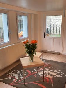 un vase de fleurs orange sur une table dans une pièce dans l'établissement Studio au calme dans jardin à 30min de Paris avec NOUVELLE LITERIE, à Chatou