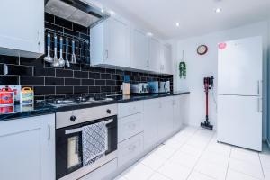 una cocina con armarios blancos y una pared de azulejos negros en West Midlands 3 Bed! Sleeps 5! Perfect for Contractors and Groups! FREE OFF STREET PARKING! 2 Bathrooms! FREE WIFI! Ideal for Long Stays, en Ocker Hill