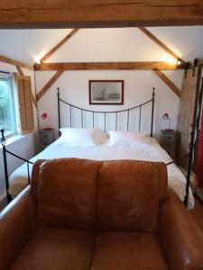 um quarto com uma cama e um sofá de couro em 4 Kingsize Beds Ensuite - Sleeps 8-10 - Rural Contemporary Oak Framed House em Chiddingfold
