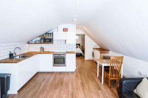 a kitchen with white cabinets and a dining room at The Loft Apartment @ Lower Coombe Royal in Kingsbridge