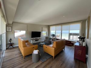 a living room with two couches and a television at Beach House at Hargraves in Norah Head