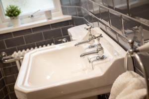 a bathroom sink with two faucets and a mirror at Woodland Cottage - cosy dog friendly cottage in the heart of Windermere in Windermere