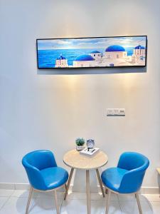 a room with two chairs and a table with a tv on the wall at The Blue Memories Homestay (Mediterranean Style) in Sungai Pelik