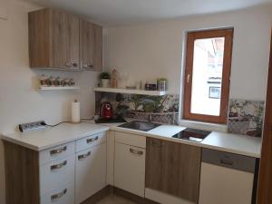 eine Küche mit Holzschränken, einem Waschbecken und einem Fenster in der Unterkunft Ferienhaus Eisenberg in Vaskeresztes
