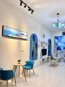 a waiting room with blue chairs and a tv on the wall at The Blue Memories Homestay (Mediterranean Style) in Sungai Pelik