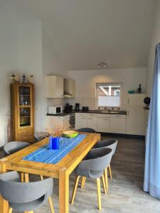 cocina con mesa de comedor de madera y sillas en Haus Petit Chateau, en Sehestedt