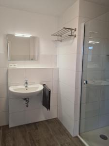 a white bathroom with a sink and a shower at Haus Petit Chateau in Sehestedt