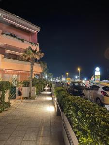 a sidewalk with cars parked in a parking lot at night at Summer House - Appartamento fronte mare in Marcelli