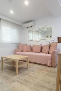 a living room with a pink couch and a table at Apartamento cerca del mar, del puerto y del centro in Valencia