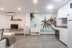 a kitchen with a painting of palm trees on the wall at Apartamento cerca del mar, del puerto y del centro in Valencia