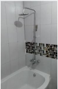 a shower in a white bathroom with a tub at Faigib Guest House in Chipata