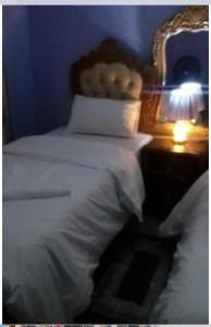 a bedroom with a white bed and a night stand with a lamp at Faigib Guest House in Chipata