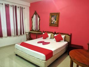 a bedroom with a bed with red walls and a table at New Richmin Hotel in Matara