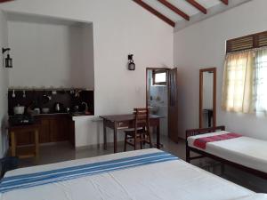 a bedroom with two beds and a kitchen with a table at The Bamboo Leaf Apartment in Hikkaduwa
