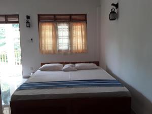 a bed in a bedroom with two windows at The Bamboo Leaf Apartment in Hikkaduwa