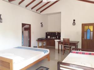 a bedroom with two beds and a table and chairs at The Bamboo Leaf Apartment in Hikkaduwa