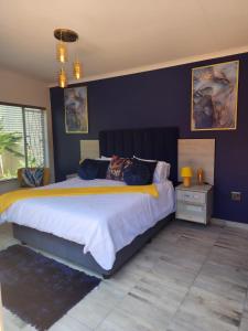 a bedroom with a large bed with a blue wall at SiBella guest house in Bloemfontein