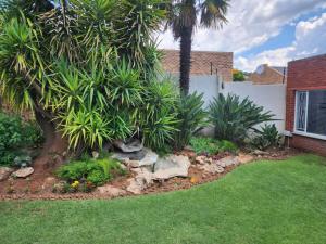 een tuin met palmbomen en bloemen in een tuin bij SiBella guest house in Bloemfontein
