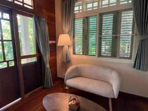 a living room with a chair and a table and windows at Home of Dusita in Lamphun