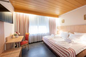 Habitación de hotel con cama, escritorio y ventana en Hotel Astoria Stuttgart City en Stuttgart