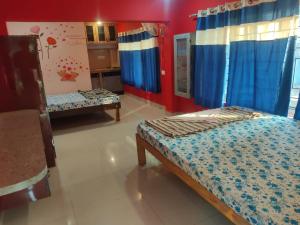 a bedroom with two beds in a room with blue curtains at Godwill Kimo Guest house Seraulim in Madgaon