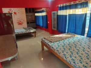 a bedroom with two beds and a red wall at Godwill Kimo Guest house Seraulim in Madgaon