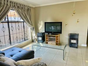 a living room with a blue couch and a tv at Mndazi Manor in Pimville
