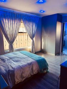 Schlafzimmer mit einem Bett und einem Fenster mit Vorhängen in der Unterkunft Mndazi Manor in Pimville
