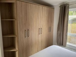 een slaapkamer met houten kasten en een raam bij Chalet Toetje op de Veluwe in Hoenderloo