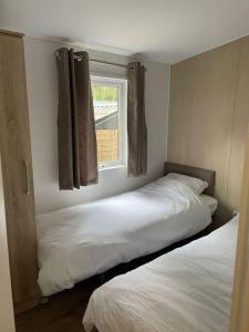two beds in a room with a window at Chalet Toetje op de Veluwe in Hoenderloo