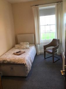 a bedroom with a bed and a chair and a window at Sea View Guest House in Hartlepool