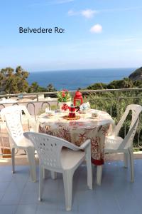 een witte tafel en stoelen met een tafel en de oceaan bij Ponzamania Appartamenti ,,Belvedere'' Ponza in Ponza