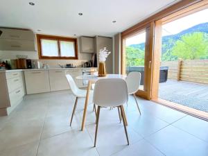 une cuisine avec une table et des chaises ainsi qu'une grande fenêtre dans l'établissement Androsace Appartement dans Chalet bois avec Jacuzzi privatif Terrasse et Vue Montagne, à Les Villards-sur-Thônes