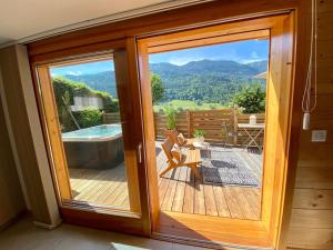 a sliding glass door with a view of a deck at Androsace Appartement dans Chalet bois avec Jacuzzi privatif Terrasse et Vue Montagne in Les Villards-sur-Thônes