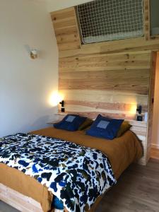- une chambre avec un lit et un mur en bois dans l'établissement Uluwatu - cottage cosy, à Saint-Laurent-de-Médoc