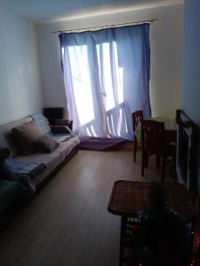 ein Wohnzimmer mit einem Sofa und einem großen Fenster in der Unterkunft Синьо небе in Bansko