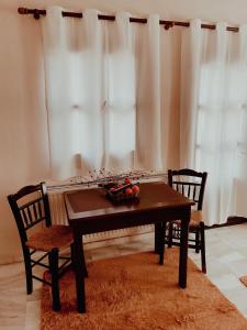 a dining room table with two chairs and a table with fruit on it at Muses Apartments in Pisoderi