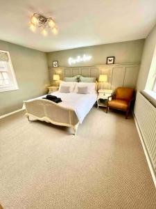 ein Schlafzimmer mit einem großen Bett und einem Stuhl in der Unterkunft Penny Black Cottage in Lavenham